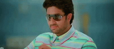A Man Wearing Sunglasses And A Striped Shirt Is Sitting Down . GIF