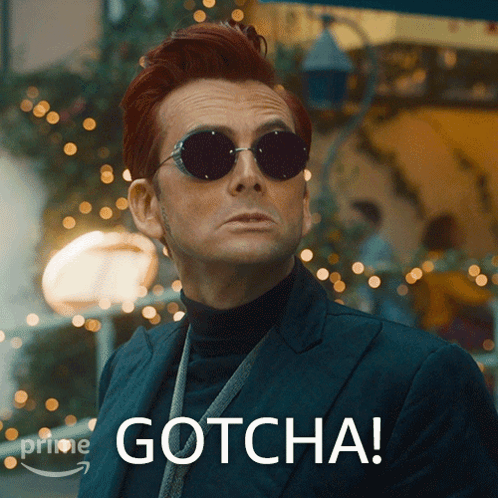 A Man Wearing Sunglasses And A Suit Has Gotcha Written On His Face GIF