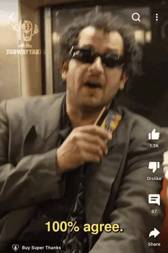 A Man Wearing Sunglasses And A Suit Is Holding A Card And Says " 100 % Agree " GIF
