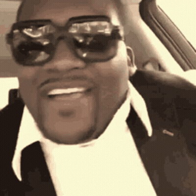 A Man Wearing Sunglasses And A Suit Is Sitting In A Car . GIF