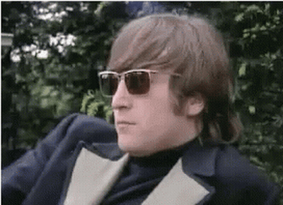A Man Wearing Sunglasses And A Suit Is Sitting On A Chair . GIF