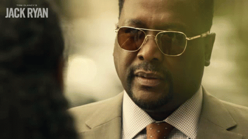 A Man Wearing Sunglasses And A Suit Talks To Another Man With The Name Jack Ryan On The Bottom GIF