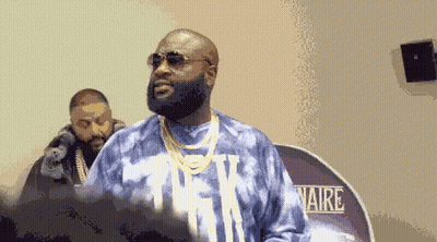 A Man Wearing Sunglasses And A Tie Dye Shirt Stands In Front Of A Sign That Says Aire . GIF