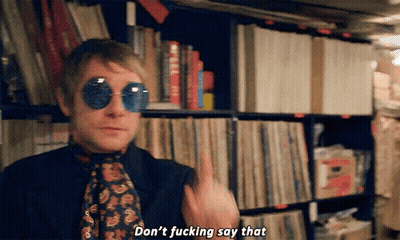 A Man Wearing Sunglasses And A Tie Is Standing In Front Of A Bookshelf And Says `` Don 'T Fucking Say That '' GIF