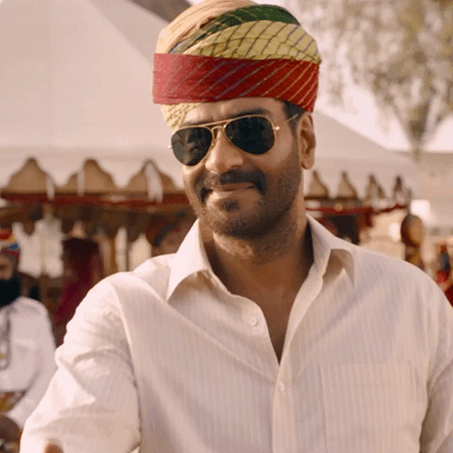 A Man Wearing Sunglasses And A Turban Is Smiling For The Camera GIF