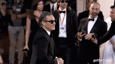 A Man Wearing Sunglasses And A Tuxedo Is Being Escorted By A Group Of Men GIF