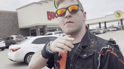 A Man Wearing Sunglasses And A Vest Is Standing In Front Of A Buck 'S Restaurant GIF