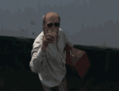 A Man Wearing Sunglasses And A White Shirt Holds A Red Bag GIF
