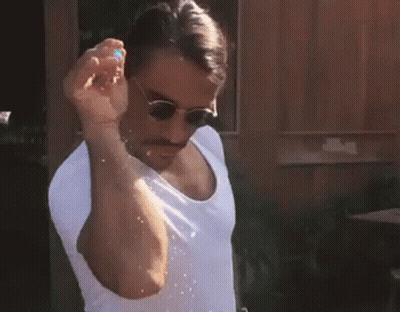 A Man Wearing Sunglasses And A White Shirt Is Holding A Balloon In His Hand . GIF