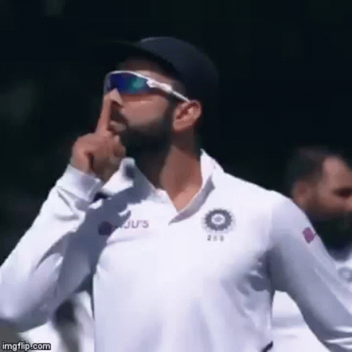 A Man Wearing Sunglasses And A White Shirt Is Holding His Finger To His Lips . GIF
