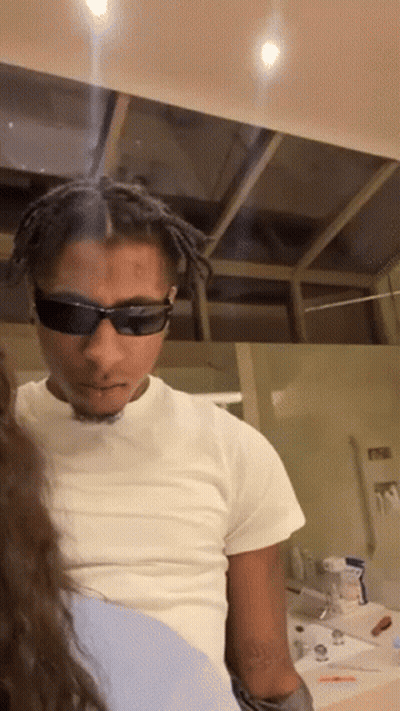 A Man Wearing Sunglasses And A White Shirt Is Looking At A Woman GIF