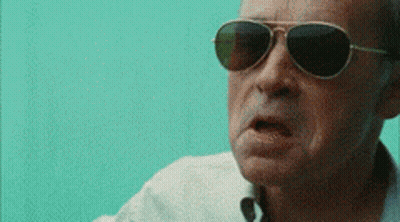 A Man Wearing Sunglasses And A White Shirt Is Making A Funny Face GIF