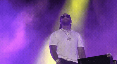 A Man Wearing Sunglasses And A White Shirt Is Standing In Front Of A Purple And Yellow Background . GIF