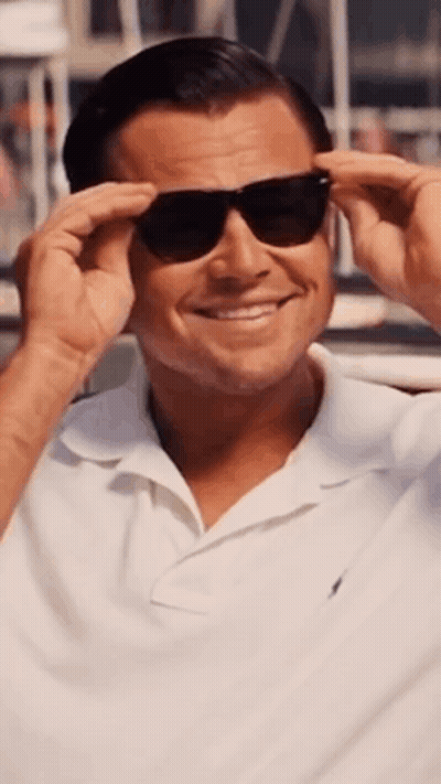 A Man Wearing Sunglasses And A White Shirt Smiles For The Camera GIF