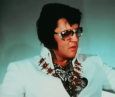 A Man Wearing Sunglasses And A White Shirt With Spikes On It GIF