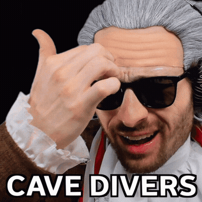 A Man Wearing Sunglasses And A Wig With The Words Cave Divers Above Him GIF