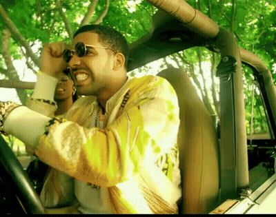 A Man Wearing Sunglasses And A Yellow Jacket Is Driving A Vehicle GIF