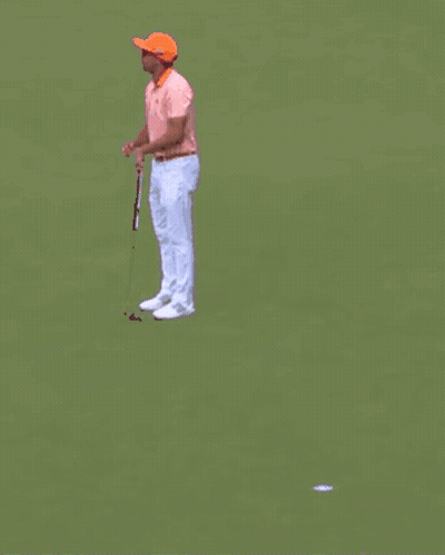 A Man Wearing Sunglasses And An Orange Hat Is Standing In Front Of A Crowd Holding A Golf Club . GIF