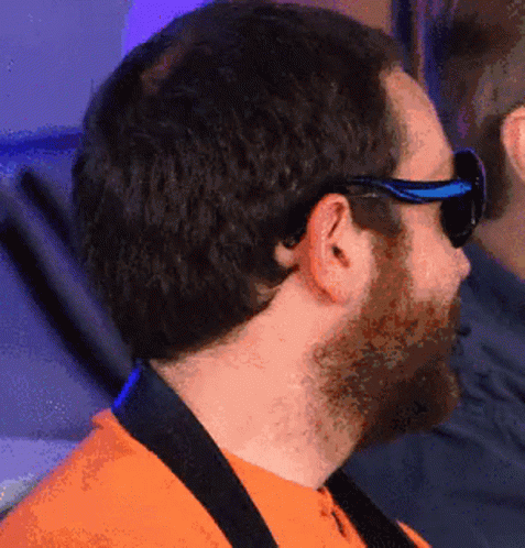 A Man Wearing Sunglasses And An Orange Shirt Looks To The Side GIF