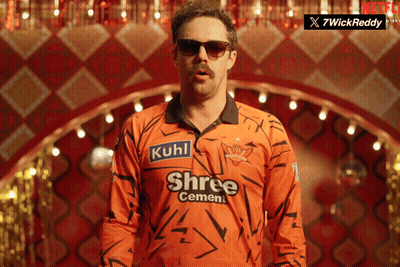 A Man Wearing Sunglasses And An Orange Shirt That Says Shree Cement On It GIF