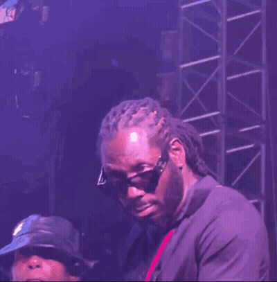 A Man Wearing Sunglasses And Dreadlocks Is Standing On A Stage GIF