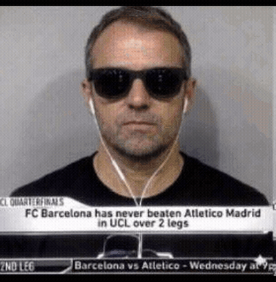 a man wearing sunglasses and ear buds is standing in front of a sign that says fc barcelona