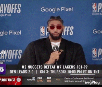 A Man Wearing Sunglasses Holds A Microphone In Front Of A Google Pixel Sign GIF