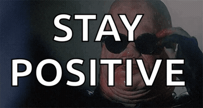 A Man Wearing Sunglasses Is Behind A Sign That Says " Stay Positive " GIF
