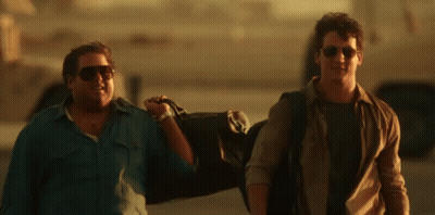 A Man Wearing Sunglasses Is Carrying A Duffel Bag GIF