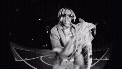 A Man Wearing Sunglasses Is Dancing On A Basketball Court . GIF