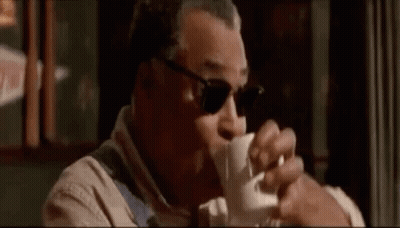 A Man Wearing Sunglasses Is Drinking A Cup Of Coffee In A Restaurant . GIF