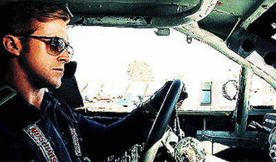 A Man Wearing Sunglasses Is Driving A Car With A Simpson Sticker On His Jacket GIF