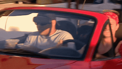 A Man Wearing Sunglasses Is Driving A Red Sports Car GIF