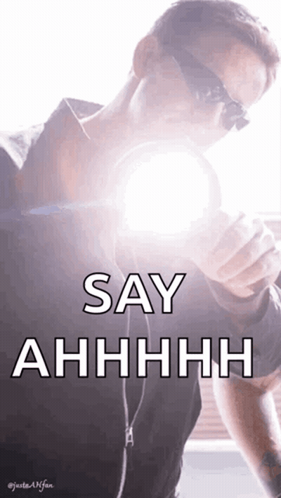 A Man Wearing Sunglasses Is Holding A Light Bulb In His Hand And Says Say Ahhhh GIF