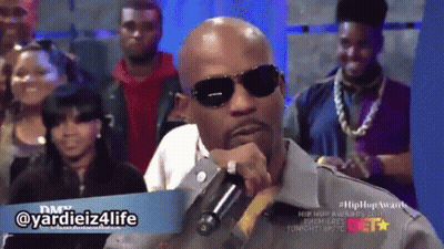 A Man Wearing Sunglasses Is Holding A Microphone In Front Of A Crowd With The Hashtag Yardiez4life GIF