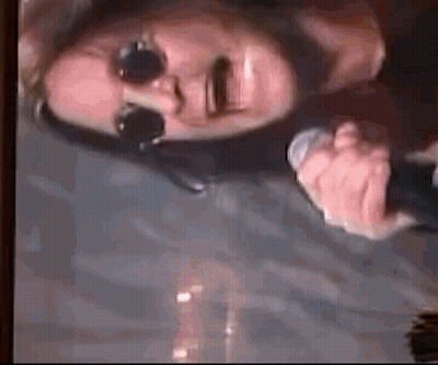 A Man Wearing Sunglasses Is Holding A Microphone In His Hand . GIF