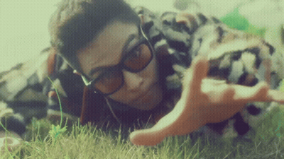 A Man Wearing Sunglasses Is Laying In The Grass With His Hands Outstretched GIF
