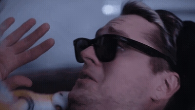 A Man Wearing Sunglasses Is Looking Through A Window GIF
