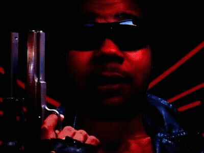 A Man Wearing Sunglasses Is Pointing A Gun At The Camera In A Red Background . GIF