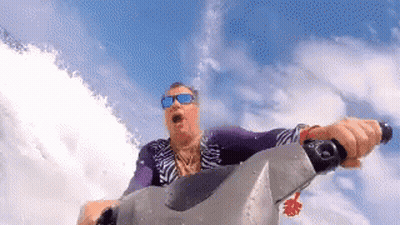 A Man Wearing Sunglasses Is Riding A Jet Ski On A Body Of Water . GIF