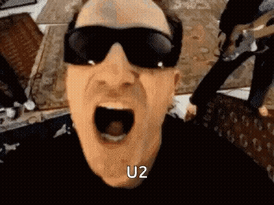 A Man Wearing Sunglasses Is Screaming With His Mouth Open And The Word U2 Written On His Face . GIF