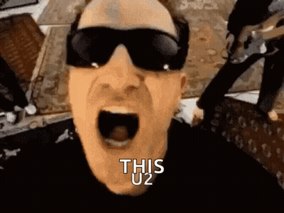 A Man Wearing Sunglasses Is Screaming With His Mouth Wide Open And The Words `` This U2 '' Written On His Face . GIF