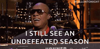 A Man Wearing Sunglasses Is Singing Into A Microphone While Sitting At A Keyboard . GIF