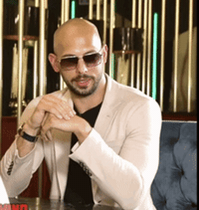 A Man Wearing Sunglasses Is Sitting At A Table GIF