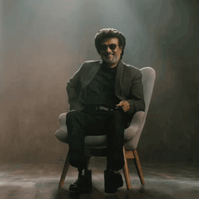 A Man Wearing Sunglasses Is Sitting In A Chair And Smiling GIF