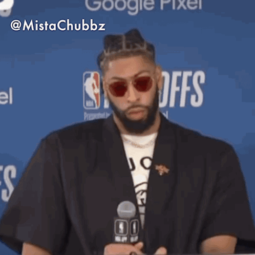 Man Wearing Sunglasses Sitting In Front Of NBA Logo GIF