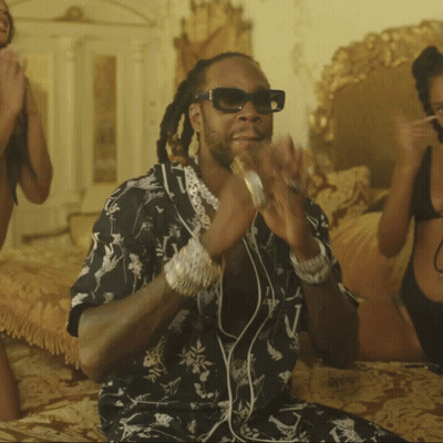 A Man Wearing Sunglasses Is Sitting On A Bed Next To Two Women In Bikinis GIF
