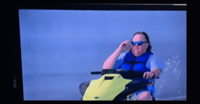 A Man Wearing Sunglasses Is Sitting On A Jet Ski GIF