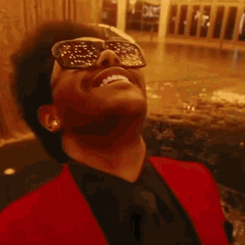 A Man Wearing Sunglasses Is Smiling With His Mouth Open . GIF
