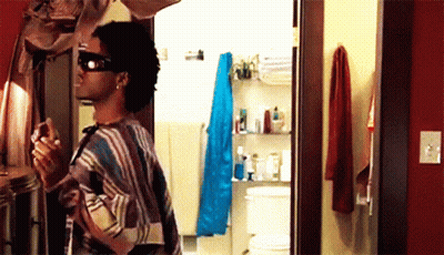 A Man Wearing Sunglasses Is Standing In A Bathroom GIF
